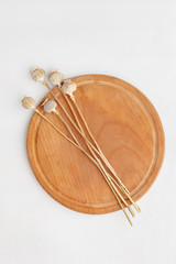 Dry poppy flowers on a wooden cutting board. Top view.
