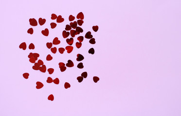 Red hearts confeetti on a pastel pink background