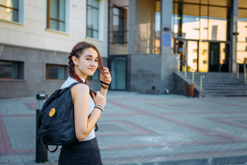 Back to school-portrait of a beautiful young schoolgirl with a backpack and long braids, education concept.