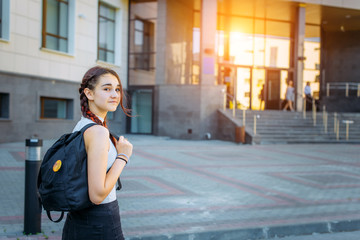 Back to school-portrait of a beautiful young schoolgirl with a backpack and long braids, education concept.