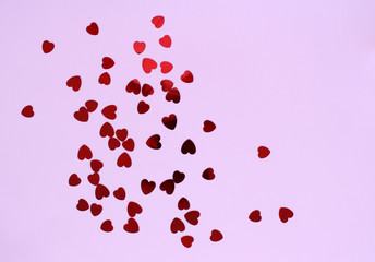 Red hearts confeetti on a pastel pink background
