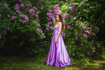 Obraz na płótnie Canvas Beautiful young woman in long dress near blossom trees in spring garden