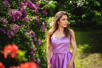 Fototapeta premium Outdoor portrait of young beautiful girl posing near the blooming lilac trees . Copy, empty space