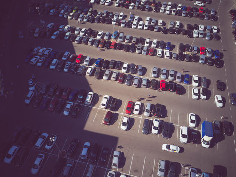 A view from above to the process of car parking. Heavy traffic in the parking lot. Searching for spaces in the busy car park. Parking advice. Cruising for parking in busy business center
