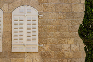 white arched closed window shutters on old brick wall simple background wallpaper pattern and tree frame , copy space 