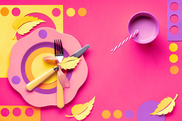 Autumn concept flat lay in bold colors with plate, fork, knife and decorative Autumn leaves