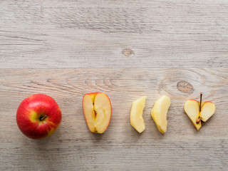 Roter Apfel im ganzen, in Spalten und in Herzform auf einem grauen Hintergrund, Flat lay