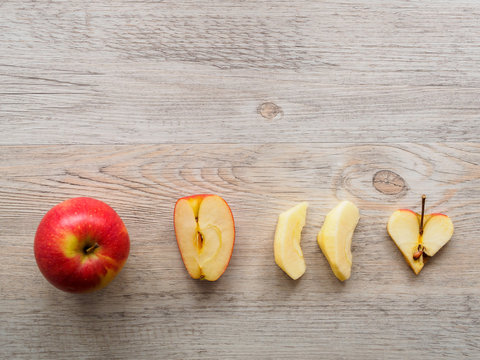 Roter Apfel im ganzen, in Spalten und in Herzform auf einem grauen Hintergrund, Flat lay