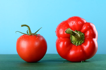 tomato and sweet pepper, paprika on the green table blue background