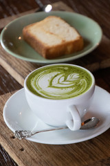 Coffee cup with Green Matcha latte art foam on wood table in coffee shop with copy space.Coffee is one of the most popular beverages.Improve Energy Levels and Burn Fat