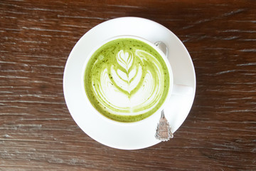 Coffee cup with Green Matcha latte art foam on wood table in coffee shop with copy space.Coffee is one of the most popular beverages.Improve Energy Levels and Burn Fat