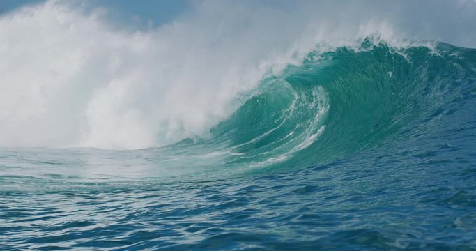 Blue ocean wave breaking and barreling with lots of power in slow motion, most epic waves on the planet