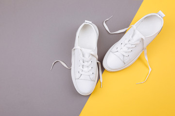 Pair of fashionable sneakers on a gray and yellow background.