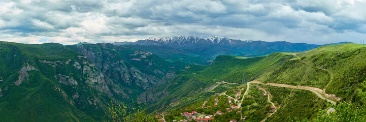 Naklejka na ściany i meble view of the village located in a mountain gorge on a bright sunny day with clouds in the sky.