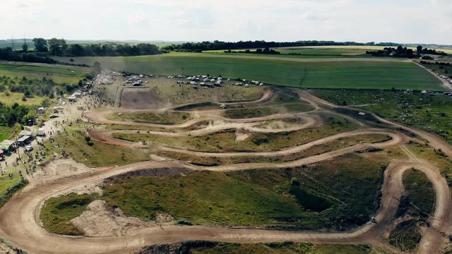 Aerial top down view of motocross track. Showing the off-road motorcycles racing on the enclosed manmade dirt circuit with steep jumps and obstacles. Wide shot. Shot on 4k camera.