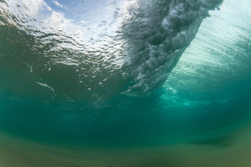 underwater view of a huge wave breaking on a beach
