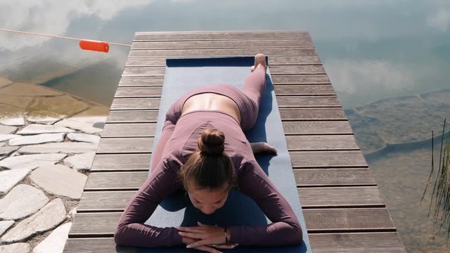 Young woman doing yoga exercises with city on background. eka pada rajakapotasana, pigeon pose