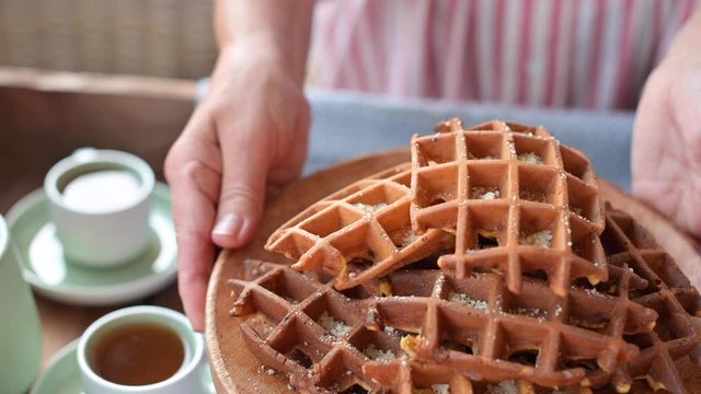 Belgian lush waffles for breakfast in female hands. Traditional homemade pastries. Lifestyle and cozy atmosphere at home. Adult woman in the frame.