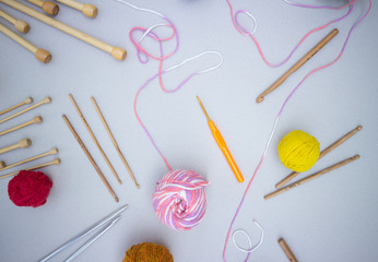 Close-up of yarn for knitting, knitting needles and crochet hooks on a white background