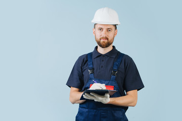 Construction engineer in a white helmet and blue uniform writing notes