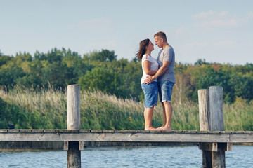 glückliches junges Paar umarmt sich am Steg am See