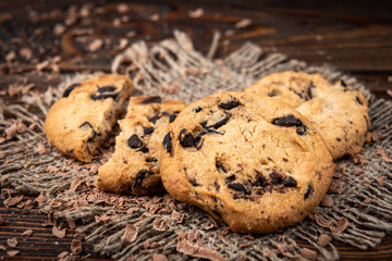 Cookies with chocolate on dark wooden background.
