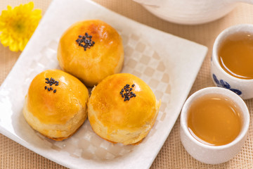 Tasty baked egg yolk pastry moon cake for Mid-Autumn Festival on bright wooden table background. Chinese festive food concept, close up, copy space.