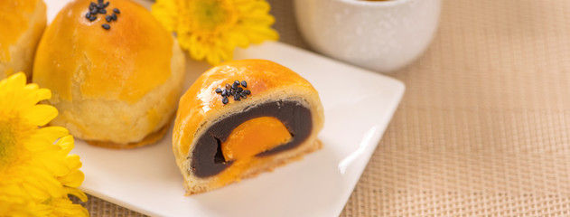 Tasty baked egg yolk pastry moon cake for Mid-Autumn Festival on bright wooden table background. Chinese festive food concept, close up, copy space.