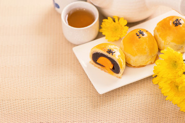 Tasty baked egg yolk pastry moon cake for Mid-Autumn Festival on bright wooden table background. Chinese festive food concept, close up, copy space.