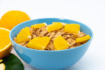 Cereal flake with pieces orange fruits slice in the blue bowl isolated on white background