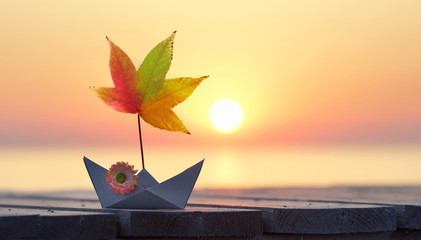Papierboot mit Herbst Blatt am Strand