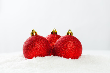 Three red baubles on white snow background. Christmas composition