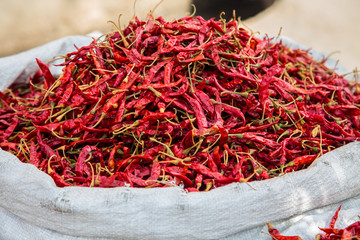 Dried red chilly kept in a gunny sack outside a shop in a spice market. background - image