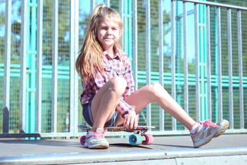 portrait of a beautiful little girl sitting on a skateboard