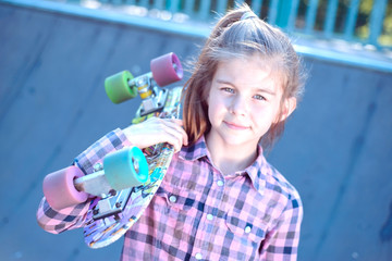 Portrait of a beautiful little girl holding a skateboard on her shoulder