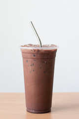 Close up reusable stainless steel straw with iced chocolate on white background.