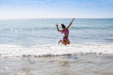 young girl jumping on the beach isolated