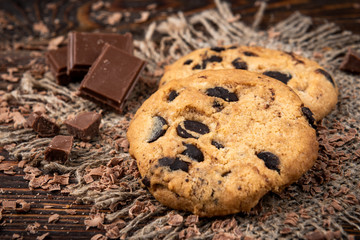 Cookies with chocolate on dark wooden background.