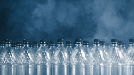 empty plastic bottles on black background with smoke, pollution concept