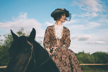 Militant independent girl in a beautiful dress of delicate brown, riding on a brown horse