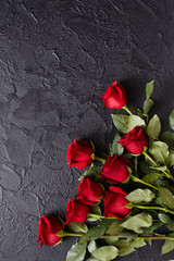 Red roses on a black, textured, stone background. Place for text, top view