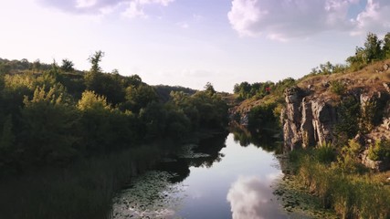 Aerial shot with drone flying close to the water in canyon during sunny day