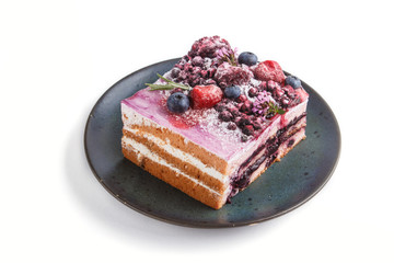 Berry cake with milk cream and blueberry jam on blue ceramic plate isolated on white background. side view.