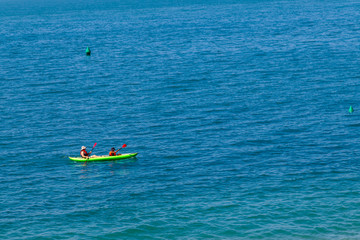Canoeing in the sea, a couple on the kayak floating in turquoise water. Water sports and summer recreations.