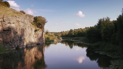 Aerial shot with drone flying close to the water in canyon during sunny day