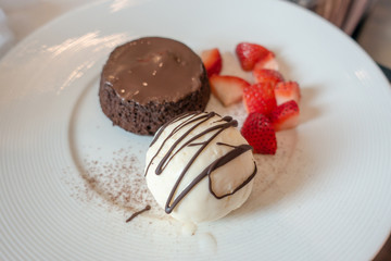 chocolate lava fondant cake with vanilla icecream, sweet dessert on white plate with strawberry.