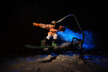 Active male snowboarder dressed in a orange sportswear jumping from the funicular