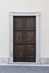 metal church door with high relief religious symbols, italy