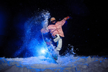 Active male snowboarder dressed in a white and pink sportswear performs tricks on the snow slope