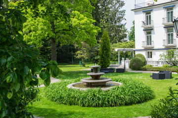 Obraz premium Fountain in green summer hotel garden.